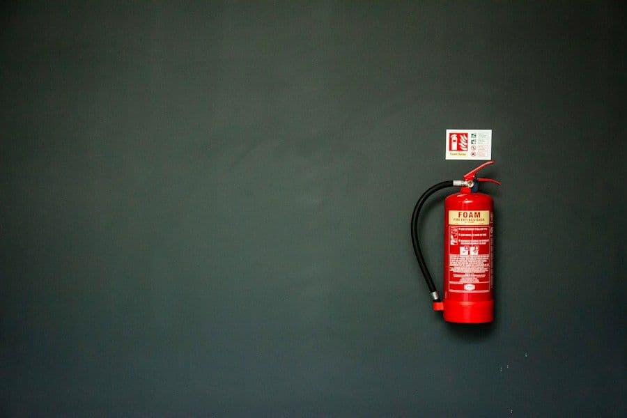 Rode brandblusser aan een donkere wand